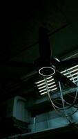 A dark concrete interior with a ceiling fan and multiple wires hanging from it video