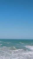 Storming sea . Action . Blue transparent water that is thrown out by waves to the shore against the background of a blue cloudless sky. video