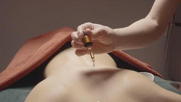 Close-up of oil dripping on back. Action. Masseur drips oil on back before massage. Massage with aromatic oils for relaxation video