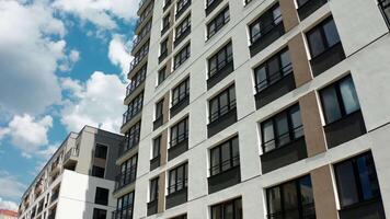 Panoramic view of facade of residential building. Stock footage. View of windows of modern apartment building on sunny day. Beautiful facade with windows of residential building in modern complex video