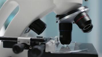 Close up of microscopic sample glass tray in laboratory. Microscope for optical test analysis with magnifying lens used in dna and bacteria research investigation and lab industry video