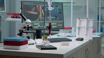 Chemical experiment with test tube in laboratory used for scientific innovation. Sample of blood in flask prepared for examination analysis on desk with vacutainers, pipette and microscope video