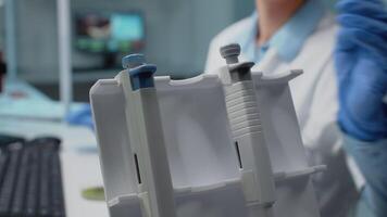 Close up of hand using micropipette in science laboratory for chemical research. Scientist with gloves grabbing dripping instrument for development while sitting at research desk video