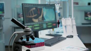 Empty laboratory with dna animation on computer and chemical equipment. Nobody in science room with documents, microscope, test tubes, micropipette and vacutainer for experiment video