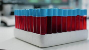 Close up of blood samples in vacutainers on medical tray in science laboratory. Transparent tubes with red dna liquid for genetic testing. Glassware flasks of coloured bio solution video