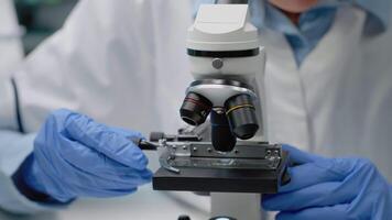 Close up of scientific microscope in laboratory and specialist hands using lens with magnifying glass for dna test and analysis. Doctor with gloves analyzing sample for investigation video