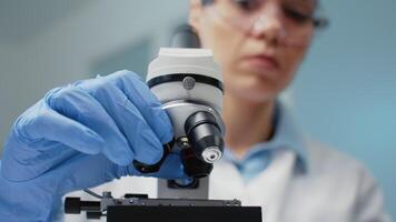 Close up of doctor using optical lens on microscope in biochemistry laboratory. Specialist using microscopic magnifying glass instrument for dna investigation and genetic bacteria video