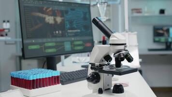 Close up of laboratory microscope on desk with medical research instruments. Empty room with micropipette, vacutainers and computer as modern technology equipment used for experiment video