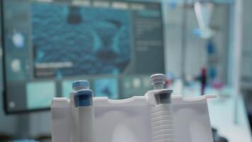 Close up of dna animation on computer and micropipette in scientific research laboratory. Empty chemical room with analysis equipment on desk. Test tube with pipe and microscope video