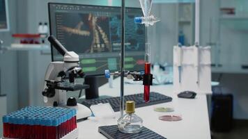 Desk with chemical equipment for experiment with test tube in laboratory. Sample of blood in flask and dripping pipe used for science with micropipette, vacutainers and microscope video
