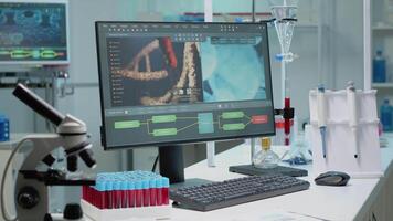 Close up of laboratory desk in hospital clinic with modern equipment and instruments for biochemistry research. Workplace with microscope, vacutainers, pipette and computer for innovation video