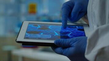 Close up of chemist doctor working on tablet with DNA scan image analysing treatment results. Scientist examining virus evolution using high tech researching vaccine development against covid19 video