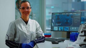 Laboratory doctor looking at camera smiling in modern equipped lab. Multiethnic team examining virus evolution using high tech and chemistry tools for scientific research, vaccine development. video