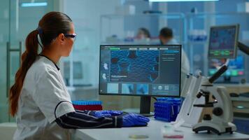 Biologist doctor checking DNA informations typing on pc in modern equipped laboratory. Scientists examining vaccine evolution in medical lab using high tech, chemistry tools for scientific research. video