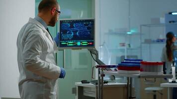 Scientist worried about virus evolution analysing DNA scan image standing in equipped laboratory typing at computer. Stuff examining vaccine development using high tech researching treatment video