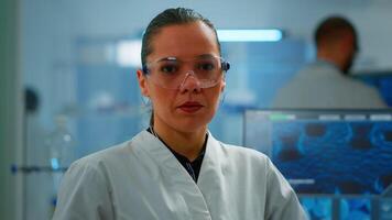 Tired chemist doctor looking at camera sighing in modern equipped lab. Multiethnic team examining virus evolution using high tech and chemistry tools for scientific research, vaccine development. video