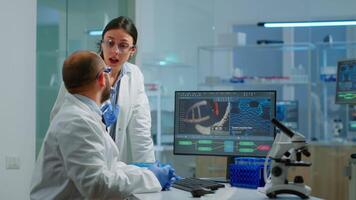 equipe médico cientista conduzindo dna experimentos olhando dentro computador segurando teste tubo com sangue amostra trabalhando dentro Ciência laboratório. laboratório engenheiros dentro branco casaco analisando vacina desenvolvimento video