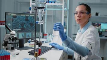 Portrait of doctor using chemical glassware on desk in laboratory for analysis. Biochemistry scientist with blood in test tube and dripping pipe for scientific healthcare development video