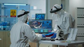 Scientists in protection suits analysing test tubes with blood sample in chemical equipped laboratory. Biologists examining vaccine evolution using high tech and technology researching treatment video