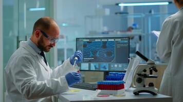 Man scientist using micropipette for filling test tubes in modern equipped laboratory. Team of researchers examining virus evolution using high tech for vaccine development against covid19 video