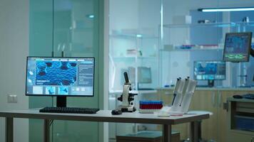 Modern empty biological applied science laboratory with technological microscopes, glass test tubes, micropipettes, desktop computers and displays. PC's are running sophisticated DNA calculations. video
