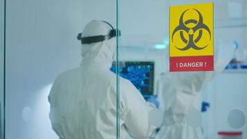 Team of chemist doctors wearing protection suit working in danger area of medical research laboratory. Scientist examining vaccine evolution using high tech for research in treatment for covid19 virus video