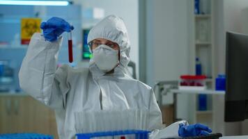 Neurologist with ppe suit working at vaccine development analysing blood sample in equipped laboratory typing on pc. Team examining virus evolution using high tech for research in treatment for covid19 video