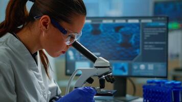 Portrait of scientist looking under microscope in medical development laboratory, analyzing petri dish sample. Medicine, biotechnology research in advanced pharma lab, examining virus evolution video