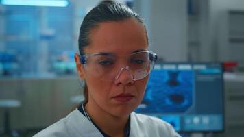Close up of tired scientist doctor looking at camera smiling working in equipped lab. Chemist examining virus evolution using high tech and chemistry tools for scientific research, vaccine development video