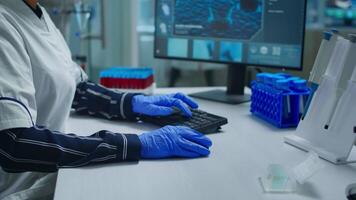 Portrait of a smiling chemist wearing safety glasses in lab looking at camera. Team of scientists doctors examining virus evolution using high tech and chemistry tools for scientific research, vaccine video
