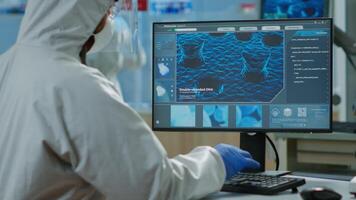 costas Visão do químico homem dentro macacão digitando em computador analisando vacina evolução dentro equipado laboratório. equipe do médicos dentro ppe terno usando Alto tecnologia para pesquisando tratamento contra covid19 vírus video