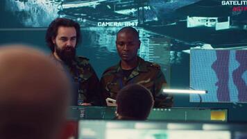 Commanders team conducting briefs to inform and update their troops on mission status and objectives, employing military satellite from a power base of operations. Information gathering. Camera A. video