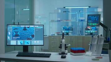 Modern empty research applied science laboratory with technological microscopes, glass test tubes, micropipettes, desktop computers and displays. PC's are running sophisticated DNA calculations. video