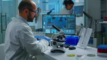 Medical research scientist conducting vaccine development under digital microscope in a biological applied science laboratory. Lab engineer working on medical treatment, typing information on computer video