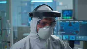 Close up of tired chemist man doctor in coverall looking at camera working in scientific equipped laboratory. Various bacteria, tissue and blood samples, pharmaceutical research for antibiotics video