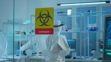 Scientist team in protective suit preparing tools for analysing virus development in danger zone of laboratory. Team of scientists analysing vaccine evolution using high tech for researching treatment video