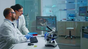 Chemist doctor explaining to coworker vaccine development, DNA mutations working in equipped laboratory. Medical biochemist stuff examining virus evolution using high tech researching diagnosis video
