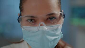 Woman wearing safety glasses during covid 19 pandemic in laboratory. Science engineer working on biochemical experiment and analysis to help with research and development in lab. Close up video