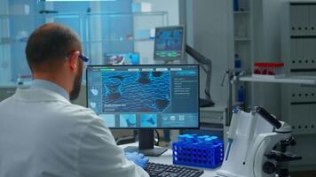 Worried chemist doctor working on pc examining vaccine evolution in scientific modern equipped laboratory. Scientist stuff using high tech and technology researching treatment against covid19 virus video