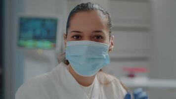 Portrait of biologist removing face mask before working in laboratory. Scientific researcher taking off protection while she works on chemistry experiment for development in lab. Close up video