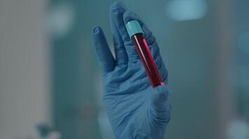 Scientist holding test tube with dna substance in laboratory for chemistry development. Science engineer analyzing glass flask with red liquid to develop biochemistry industry. Close up video