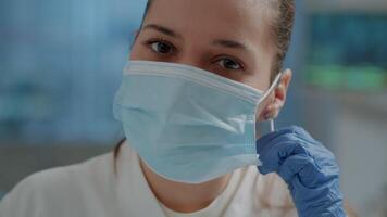 Chemistry engineer taking off face mask in science laboratory, getting ready to work on microbiology experiment for development and research. Woman working on discovery in lab. Close up video