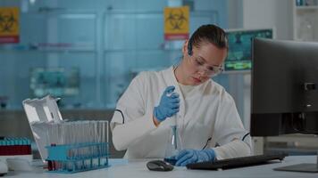 Scientist working with micro pipette for liquid in beaker and test tube, doing chemistry experiment in laboratory. Biochemistry researcher mixing substance using dropper and lab equipment. video