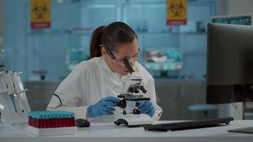 Portrait of chemist working with microscope in laboratory, to develop science experiment. Microbiology specialist using optical tool with microscopic lens to analyze dna sample in lab. video