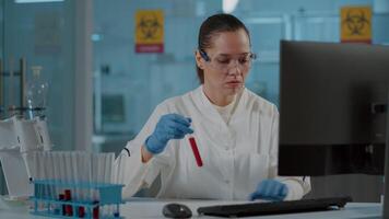 Chemistry researcher looking at substance in test tube for experiment in science laboratory. Woman scientist analyzing dna sample in glass flask, working on biology development in lab. video
