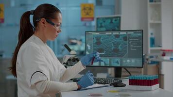 Biologist analyzing liquid in test tube and using computer to work on scientific development in laboratory. Specialist working on monitor with dna substance in flask, holding lab glassware. video