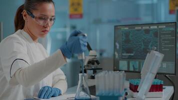 Chemist working on experiment with micro pipette and beaker, using dropper on test tube to develop science industry in laboratory. Woman scientist doing lab work with equipment and tools. video