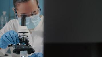 Specialist working with microscope in science laboratory, using microscopic tool and magnifying glass lens to examine dna substance. Chemist analyzing microbiology genetic. Close up video