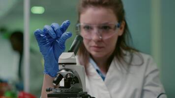 Closeup of scientist woman looking at test sample of leaf analyzing for biological experiment with organic plants. Biologist specialist discovering organic gmo plants while working in microbiology lab video