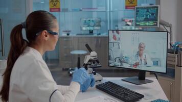 chimico utilizzando in linea chiamata su computer nel laboratorio per opera con scienza esperto per sviluppo. microbiologo parlando per donna su a distanza Teleconferenza, comunicazione. video